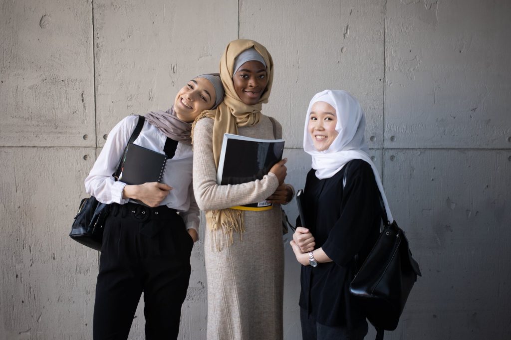 positive multiracial muslim women with workbooks in university